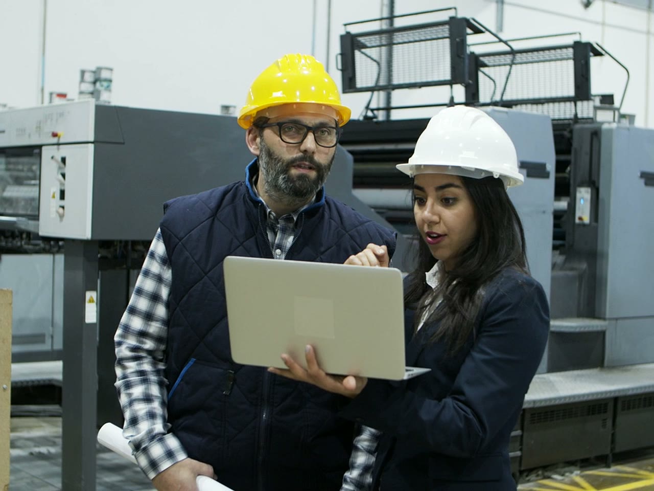 Senior engineer reviewing a spec with a colleague on the shop floor